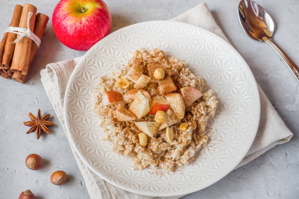 istock Oatmeal with fresh apples, nuts and cinnamon for Breakfast on the table, close-up, horizontal 1055427172