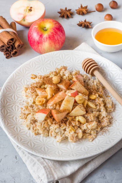 istock Oatmeal with fresh apples, nuts and cinnamon for Breakfast on the table, close-up, vertical 1055429760