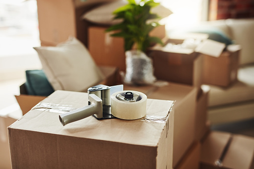 Still life shot of a tape dispenser on a cardboard box in a house