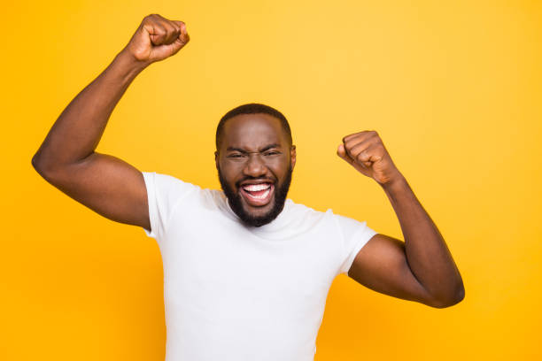 istock Handsome attractive manly cheerful glad man, showing winning yes cool gesture, celebrating, isolated over bright vivid yellow background 1055430278