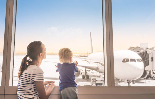 Mother and son in the airport Mother and son at airport boarding terminal looking out window at airplane. Family travel and adventure. airports canada stock pictures, royalty-free photos & images