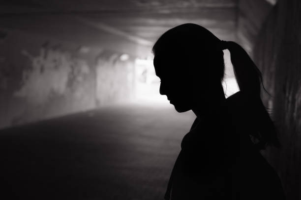 Depressed young women in the tunnel Depressed sad young female standing in a dark tunnel person shadow stock pictures, royalty-free photos & images