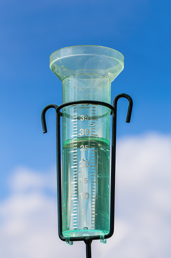 Water meter with rainwater, a white cloud and blue sky. I took this photo in the netherlands during summer season. Since a very long drought period it finally rained. With this tool you can see how much water there was fallen from the sky.