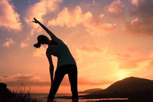 Healthy young woman warming up outdoors stretching her arms.