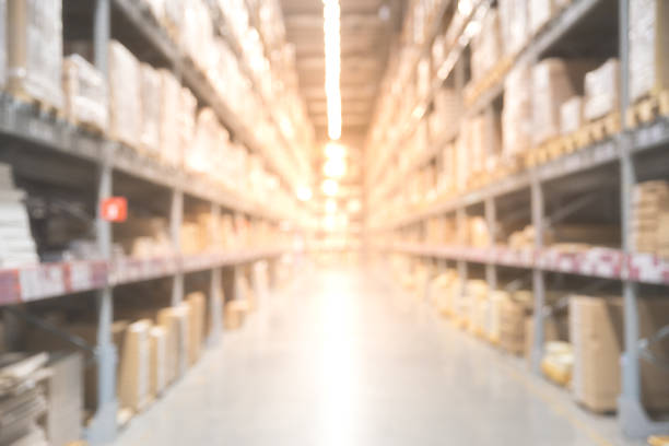 istock Blurred boxes on rows of shelves in warm light warehouse background. 1055439794