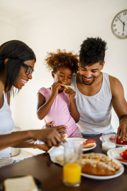 istock Young happy family having breakfast at home 1055440698
