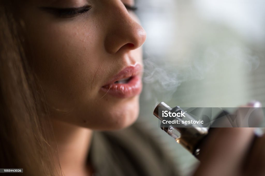Donna che fuma una sigaretta elettronica - Foto stock royalty-free di Sigaretta elettronica