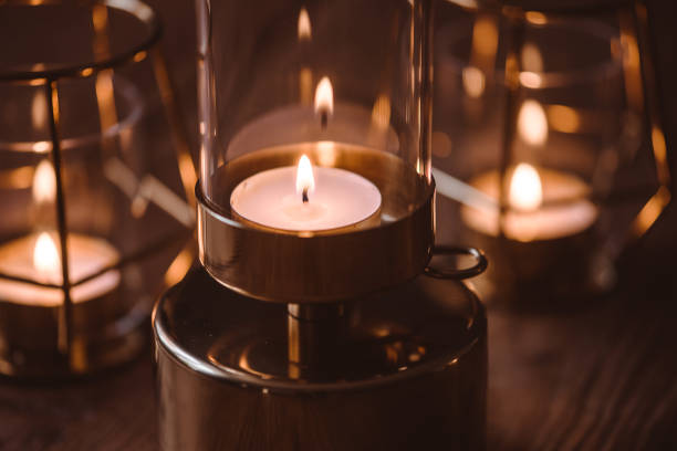 Candlelight in light holders standing on wooden tablePhoto taken indoors in natural light of burning tea lights