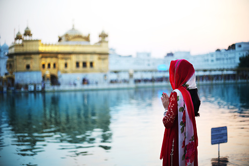 Mujer joven orando a Dios en el templo de oro, India photo