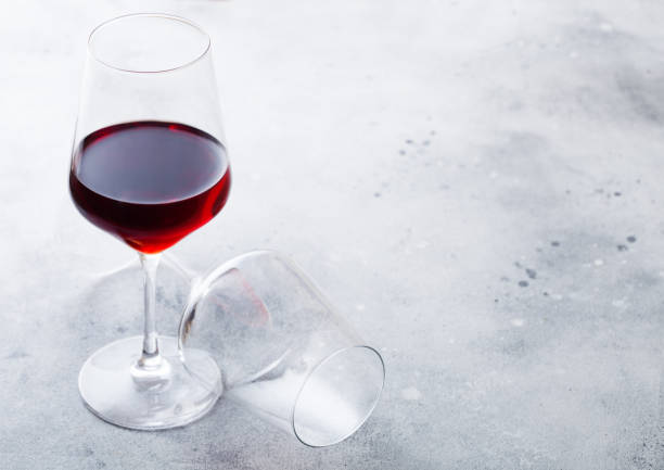 istock Elegant glasses of red wine on stone kitchen table background. 1055449082