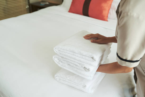 istock Crop woman arranging stack of towels on bed 1055454128