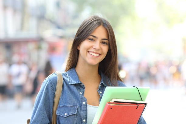estudiante feliz posa mirando a cámara en la calle - book young adult women student fotografías e imágenes de stock