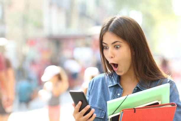 istock Surprised student girl watching phone content 1055454910