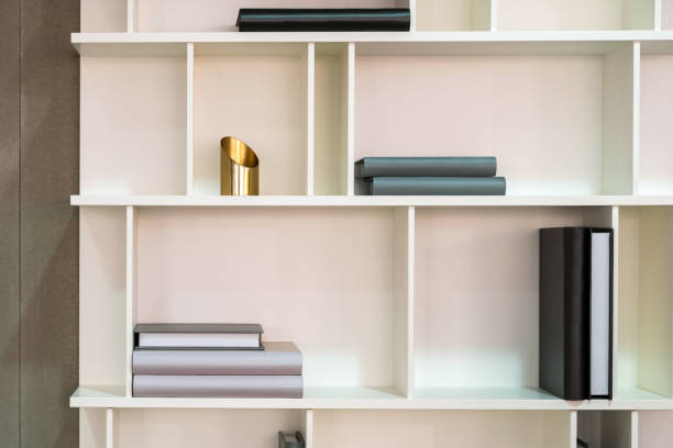 White wooden shelf indoor with different home related objects. Books, vase