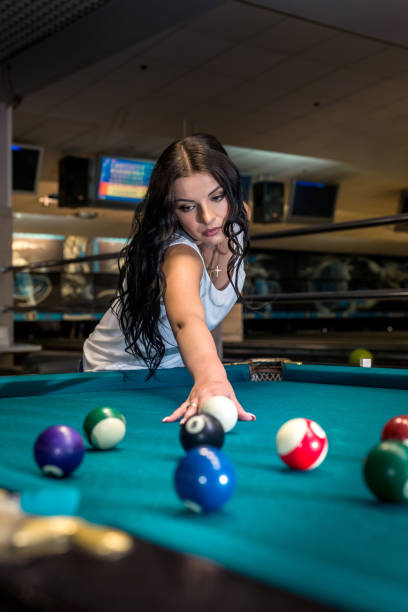 istock Beautiful brunette woman playing billiard in pub 1055461536