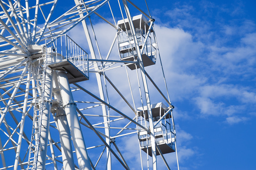 White ferris wheel against the blue sky. Ferris wheel in the park.
