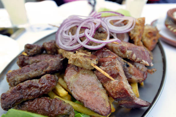 Various grilled meat on a metal plate on the table in the restaurant