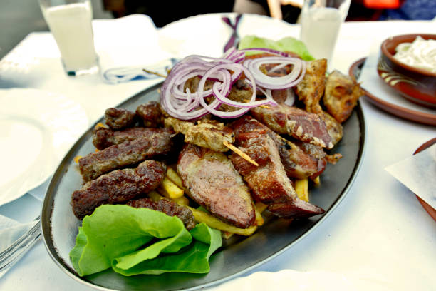 Various grilled meat on a metal plate on the table in the restaurant