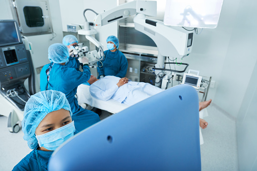 From above shot of Asian surgeons using modern equipment to perform surgery in operating theatre
