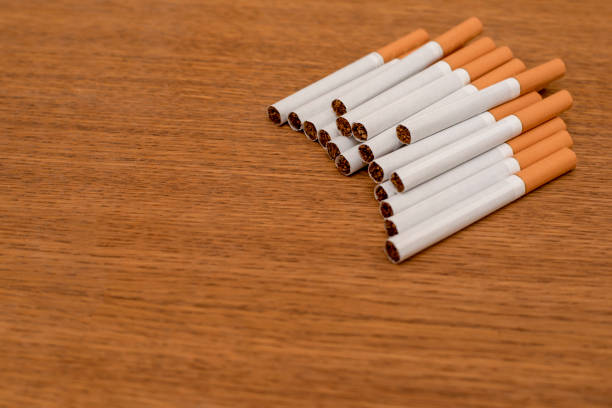 istock Pack of white cigarettes with orange filter on wooden 1055471238