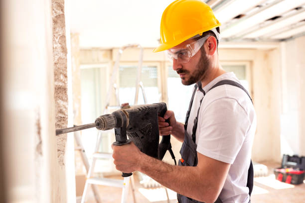 Electrician working with masonry tools Electrician working with masonry tools wearing protective and safety gear helmet hardhat protective glove safety stock pictures, royalty-free photos & images