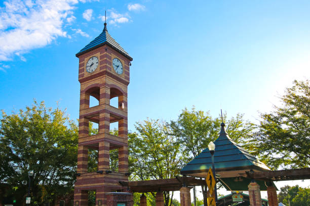 Woburn, MA / USA - Oct 13, 2018: Street view of a Woburn Square street clock and the Italianete-style First Church of Woburn on a rainy autumn morning. Built in 1860, the church is a local landmark and features a 196 foot wooden steeple, which is considered to be the tallest in North America. The church has a spire and clock tower, plus it houses a rare organ. The congregation, established in 1642, was originally Puritan and is one of the oldest in the United States. Woburn is located near Boston in Middlesex County, Massachusetts, New England, United States.