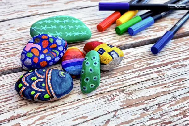 Hand-painted colorful stones and acrylic pens on a vintage textured wooden table