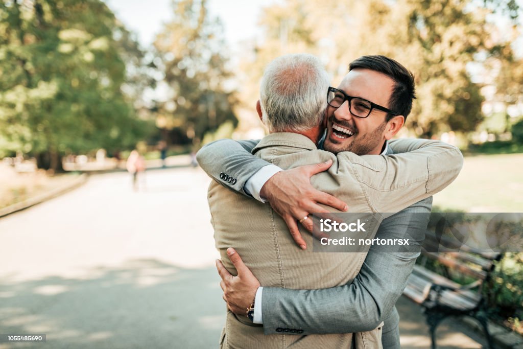 Riunione di famiglia. Padre e figlio che si abbracciano all'aperto. - Foto stock royalty-free di Padre