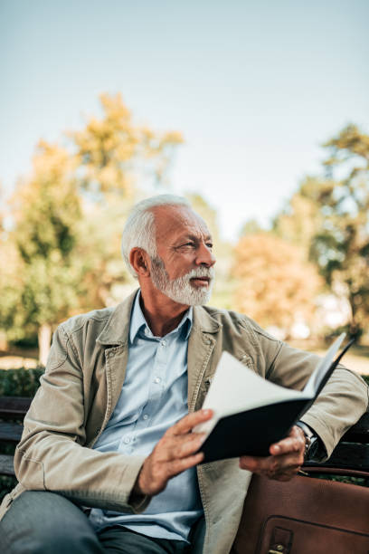 istock Senior man reading a book on a bench. 1055485714