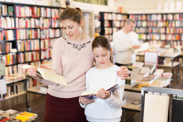 istock Woman with daughter looking for books in library 1055488052