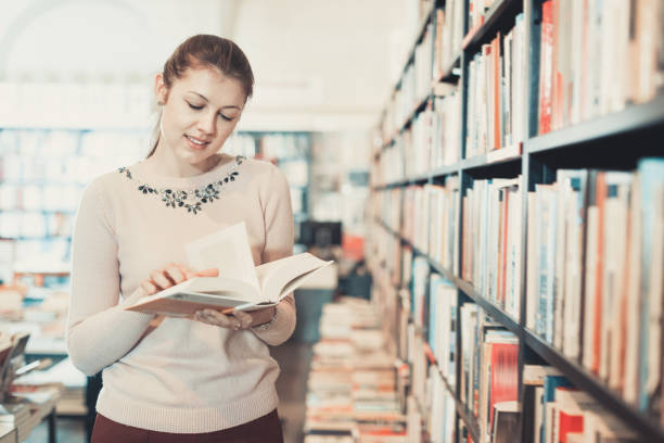 istock Young woman browsing inside of books while visiting public libra 1055489168
