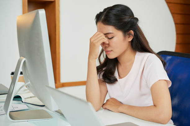 istock Tired young woman at table in office 1055492066