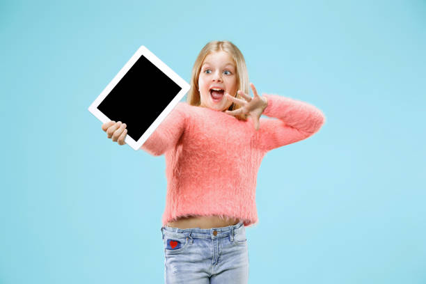 istock Little funny girl with tablet on blue background 1055492926