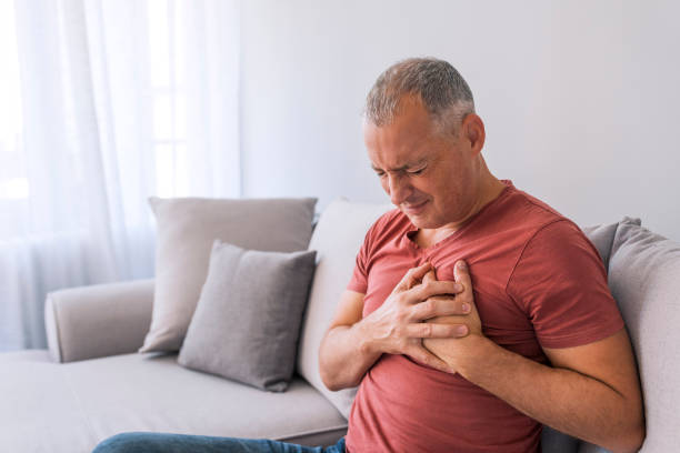 Reoccurring pain should be treated immediately Severe heartache, man suffering from chest pain, having heart attack or painful cramps, pressing on chest with painful expression. Photo of Mature man suffering from chest pain at home during the day. endocarditis stock pictures, royalty-free photos & images