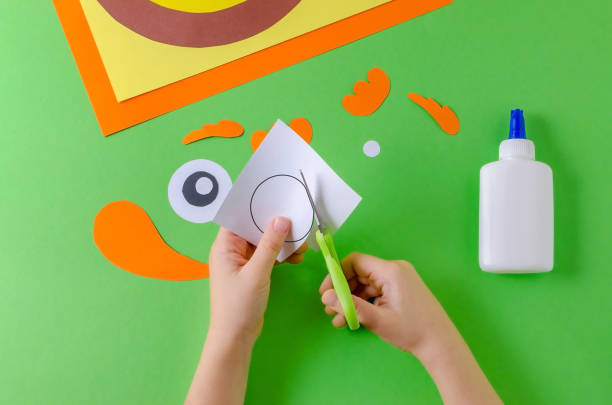 istock child cuts paper circle, view from above, glue and scissors on green 1055496468