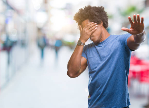 istock Afro american man over isolated background covering eyes with hands and doing stop gesture with sad and fear expression. Embarrassed and negative concept. 1055500928
