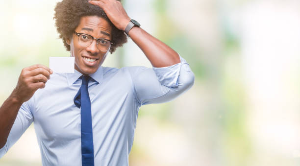 istock Afro american man holding visit card over isolated background stressed with hand on head, shocked with shame and surprise face, angry and frustrated. Fear and upset for mistake. 1055501358