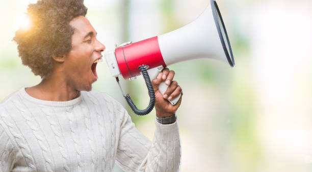 istock Young handsome afro american black man shouting through megaphone 1055502184