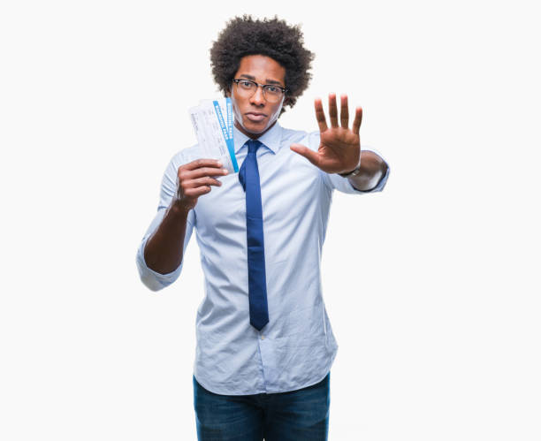 istock Afro american man holding boarding pass over isolated background with open hand doing stop sign with serious and confident expression, defense gesture 1055503568