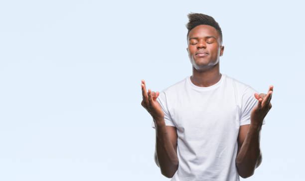 istock Young african american man over isolated background relax and smiling with eyes closed doing meditation gesture with fingers. Yoga concept. 1055505486