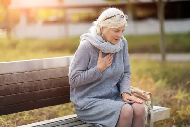 Photo of Senior Woman Suffering From Chest Pain While Sitting On Bench