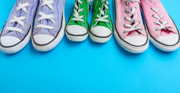 istock three pair of old worn textile sneakers on a blue background 1055509842