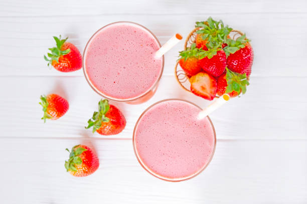 Strawberry smoothies red colorful fruit juice milkshake blend beverage healthy high protein the taste yummy In glass drink episode morning on wood white background from top view.