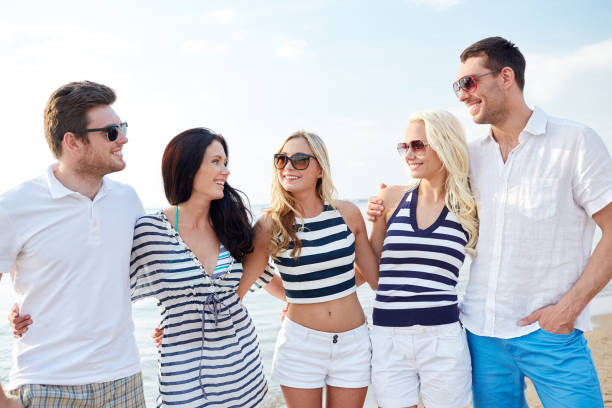 istock smiling friends in sunglasses talking on beach 1055511196