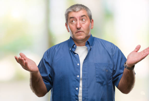 istock Handsome senior man over isolated background clueless and confused expression with arms and hands raised. Doubt concept. 1055521066