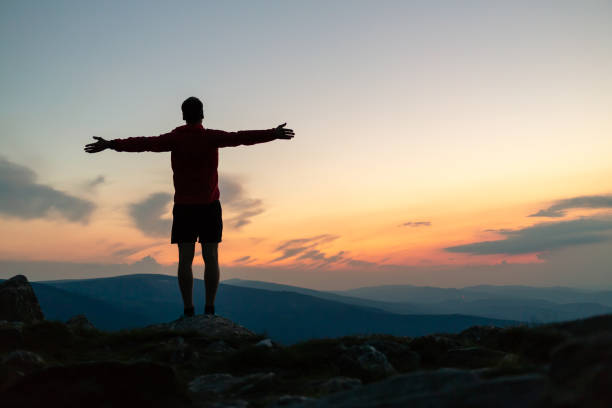 istock Man celebrating sunset looking at view in mountains 1055521108