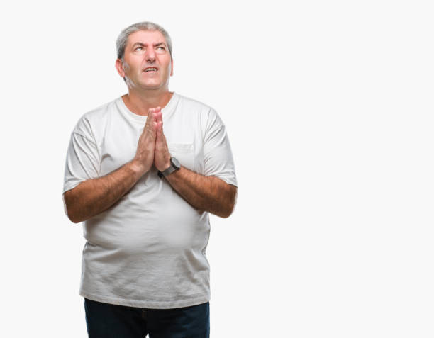 istock Handsome senior man over isolated background begging and praying with hands together with hope expression on face very emotional and worried. Asking for forgiveness. Religion concept. 1055522404