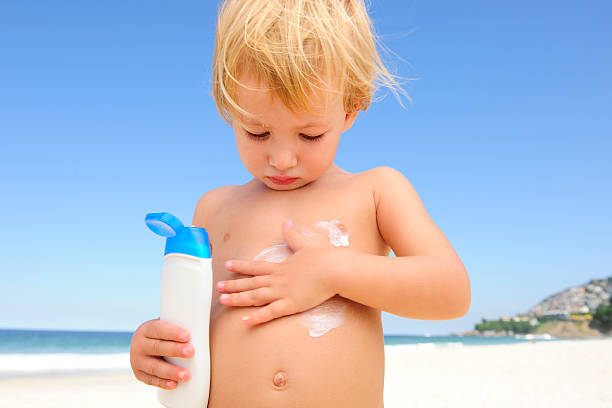 istock cute child applying  suntan lotion at the beach 105552522