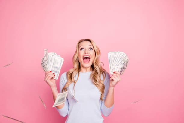 portrait of shocked surprised girl having shower from a lot of money yelling with wide open mouth isolated on pink background - smiling casino human hand beautiful imagens e fotografias de stock