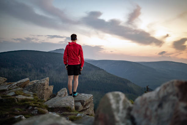 istock Man celebrating sunset looking at view in mountains 1055528558